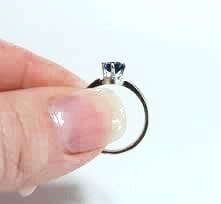 Fingers holding side of ring with stone facing up.